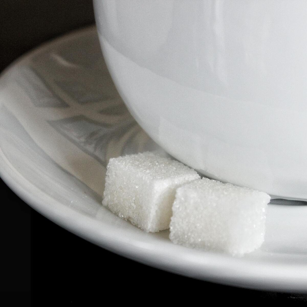 Cubos de açúcar no prato de uma xícara. 